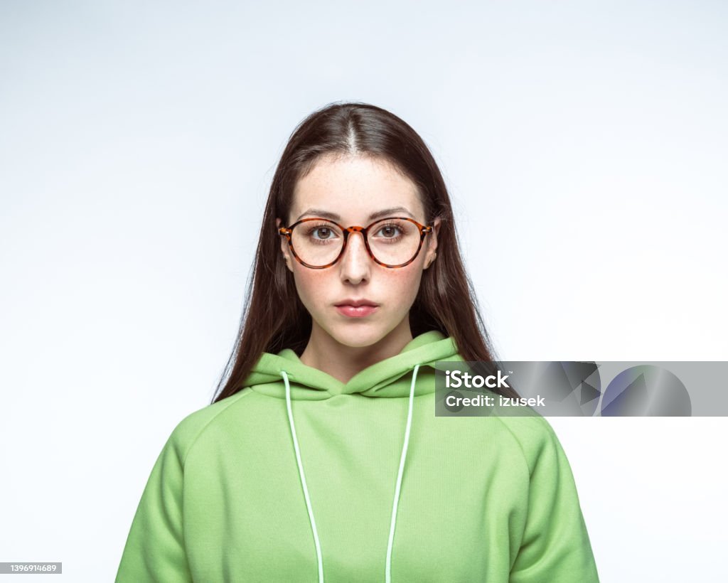 Confident woman over white background Portrait of confident young woman with long brown hair wearing eyeglasses against white background Cut Out Stock Photo