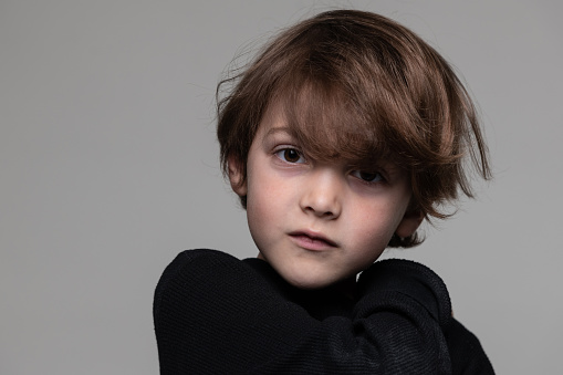 caucasian little schoolboy looking at the camera on gray background