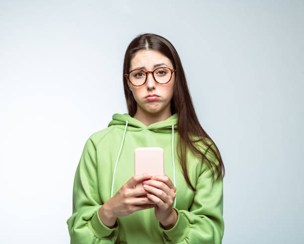 istock Sad woman standing with mobile phone 1396915674