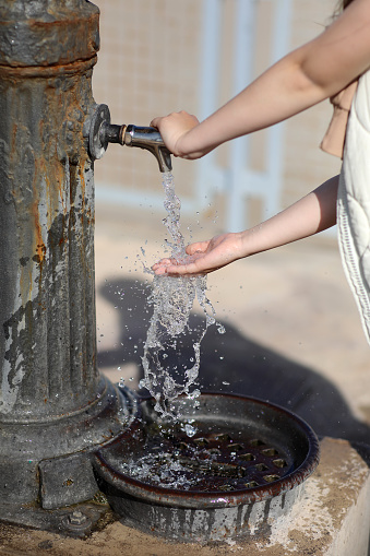 child hands under drinking fresh water tap on the beach on a bright Sunny day by the sea. High quality photo.