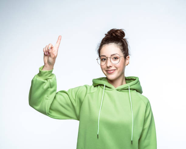 Smiling woman pointing up over background stock photo