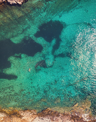 Aerial view of young woman swimming in crystal blue sea on the Greek island Thassos