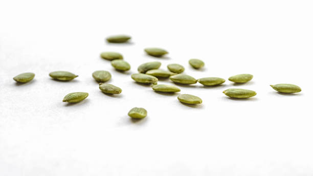 Raw peeled pumpkin seeds scattered on a white background, top view stock photo