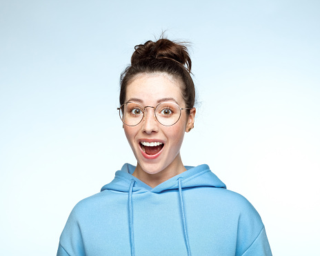 Portrait of excited young woman in eyeglasses against white background.