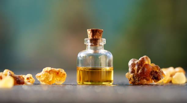 A bottle of frankincense essential oil with frankincense resin on a table stock photo