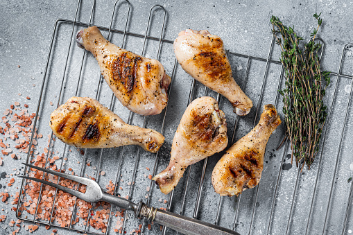 Grilled Jerk Chicken on a grill, leg drumstick poultry meat. Gray background. Top view.