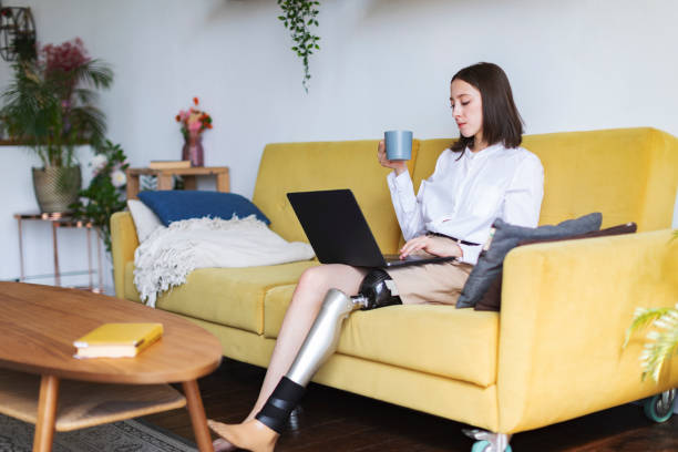 istock Young woman amputee with prosthesis working on laptop at home 1396920775