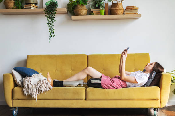 istock Young woman amputee with prosthesis relaxing with mobile at home 1396920928