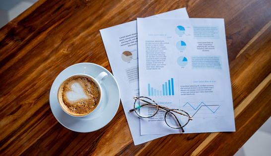 Cup of coffee and business documents on the table at a cafe  - food service concepts