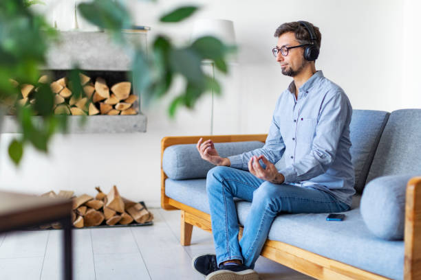 istock Young man meditating at home with mobile application 1396921810