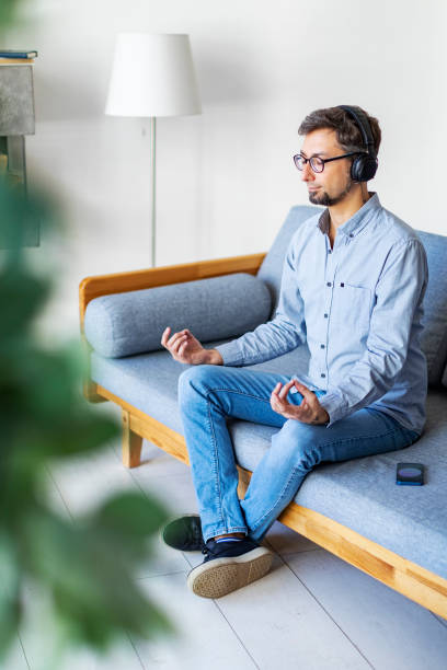 istock Young man meditating at home with mobile application 1396921811