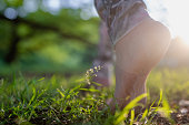 Close-up photo of a woman's bare feet while walking on grass and soil in nature