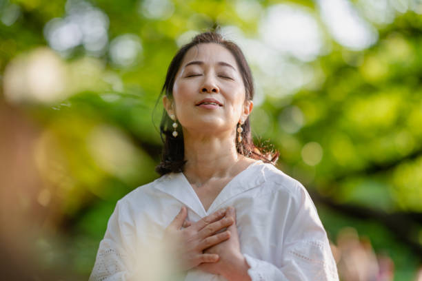 mujer meditando en la naturaleza - exhalar fotografías e imágenes de stock