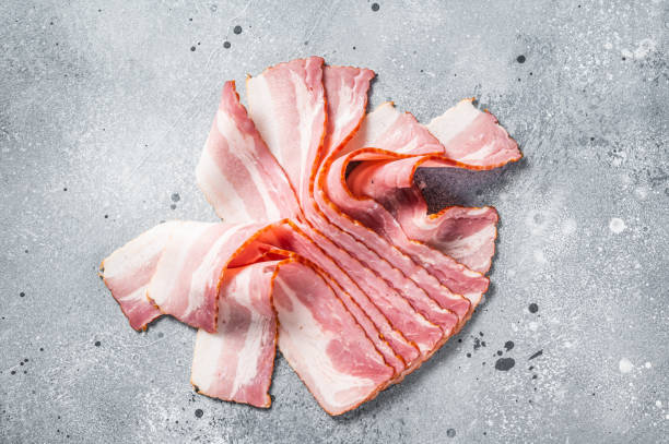 istock Raw bacon strips of pork meat. Gray background. Top view 1396923334