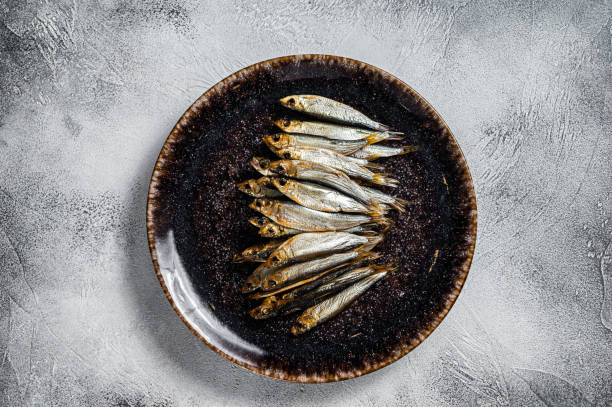 istock Smoked sprat fish in rustic plate. White background. Top view 1396924083