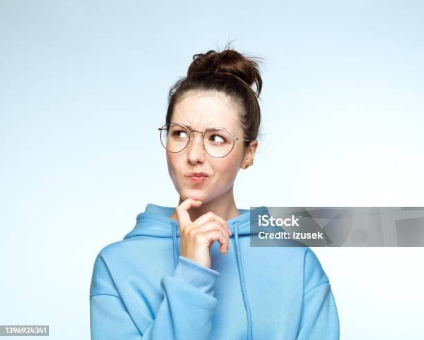 Woman In Blue Hooded Shirt With Hand On Chin Stock Photo - Download Image Now - 20-24 Years, Adult, Adults Only