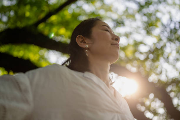 ผู้หญิงยื่นแขนของเธอใต้ต้นไม้ในธรรมชาติ - forest bathing ภาพสต็อก ภาพถ่ายและรูปภาพปลอดค่าลิขสิทธิ์