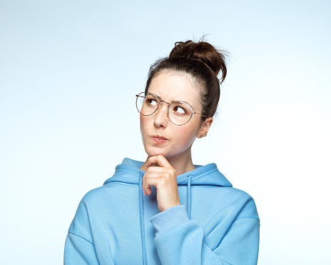 Thoughtful woman with hand on chin looking up against white background