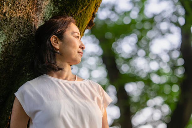 istock Woman leaning against tree trunk and watching sunset in nature 1396924568