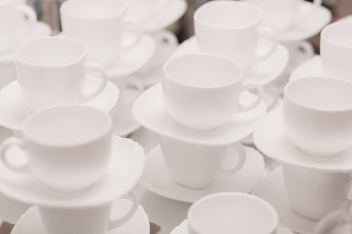 a lot of rows of pure white cups with plates for coffee or tea break . High quality photo.