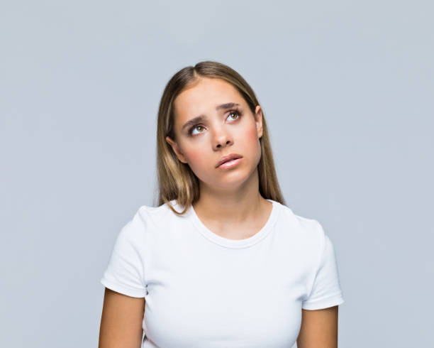 adolescente pensativa con camiseta blanca - decisions teenage girls horizontal studio shot fotografías e imágenes de stock