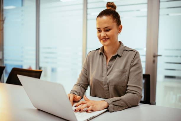 istock Female manager working in office on laptop and smiling 1396929558