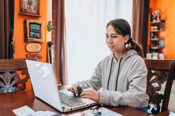 Teen girl using laptop at home A day in the life of a Chilean family living in a residential neighborhood in the capital Santiago. high school enrollment stock pictures, royalty-free photos & images