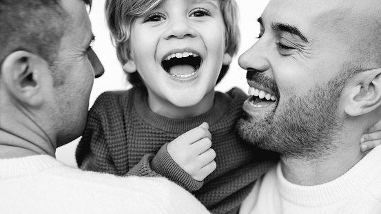 Gay male couple of fathers and son having fun outdoor - LGBT diversity and family love concept - Black and white editing