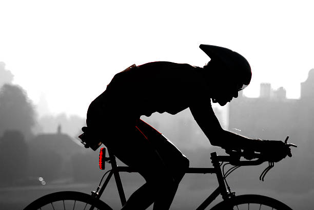 Silhouette of man on bicycle racing in the city stock photo