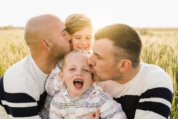 gay male parents having fun with their sons outdoor in summer day - lgbt family concept - soft focus on little child face - child little boys male caucasian imagens e fotografias de stock
