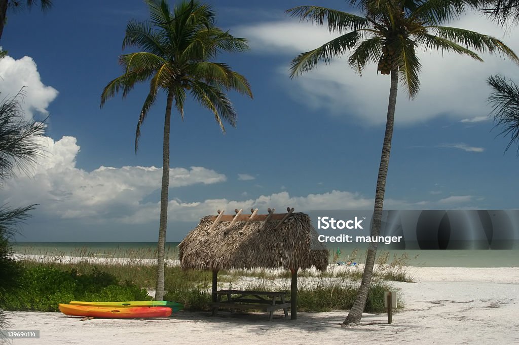 Sanibel Island Palms and Hut Beautiful photo of a picnic table under a grass hut on the island of Sanibel Florida. Sun is high (near noon) and there are beautiful summer clouds in the back. Beach Stock Photo