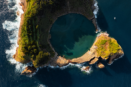 Spectacular drone scenery of island in shape of circle, and lagoon with rocky formations located in sea near Vila Franca on Sao Miguel in Portugal