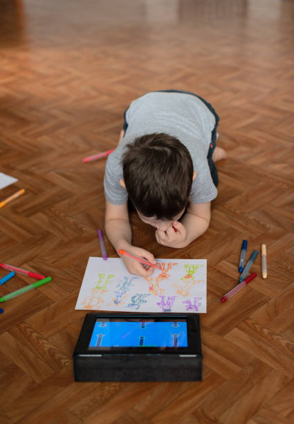 istock Child boy sitting on the floor with tablet playing games or studying something on it and drawing a picture. Social and technology concept 1396946538