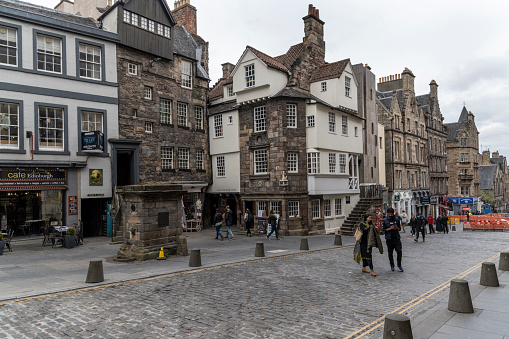 Tourists on The Royal Mile, the main thoroughfare of the Old Town of the city of Edinburgh in Scotland on the cloudy day. The Royal Mile runs between two significant locations in the royal history of Scotland: Edinburgh Castle and Holyrood Palace.