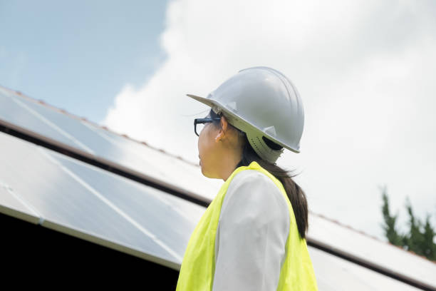 une ingénieure portant un casque et un uniforme inspecte et entretient l’équipement photovoltaïque d’une centrale solaire. concept d’énergie alternative - solar panel engineer solar power station women photos et images de collection