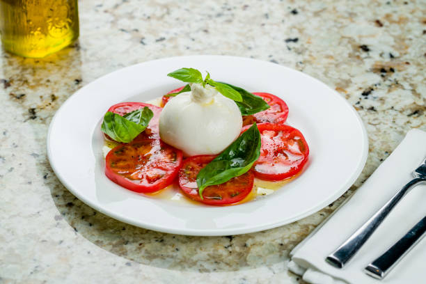 salada com queijo buratta e tomates com manjericão no prato branco na mesa de mármore - buratta - fotografias e filmes do acervo