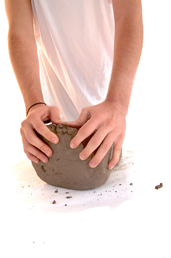 Hands molding grey clay. 