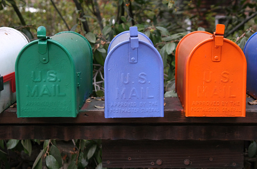 Rows of colorful numbered mailboxes in a built shingled shed along a Cape Cod roadway.