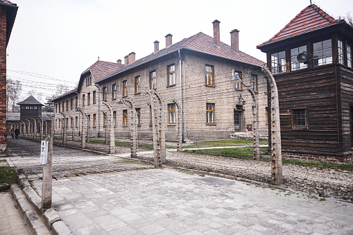 Oswiecim, Poland - March 31, 2014 : View of electric fence with barbed wire between buildings in the former Nazi concentration camp Auschwitz-Birkenau