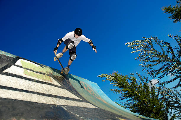 A skateboarder wearing gear in action on an outdoor ramp stock photo