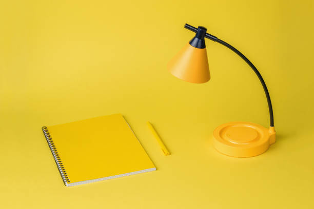 istock Minimal concept. A notebook, a pen and a yellow desk lamp on a yellow background. 1396965737