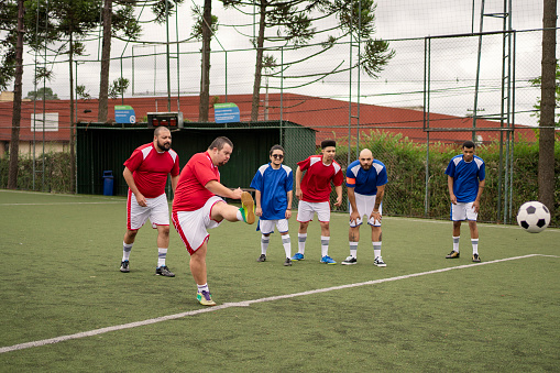 Soccer player with Down Syndrome kicking the ball during friendly game