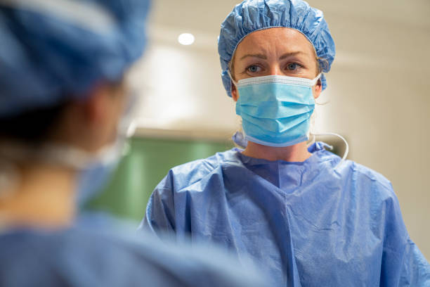 istock Female surgeon wearing protective workwear talking to nurse during surgery 1396967768