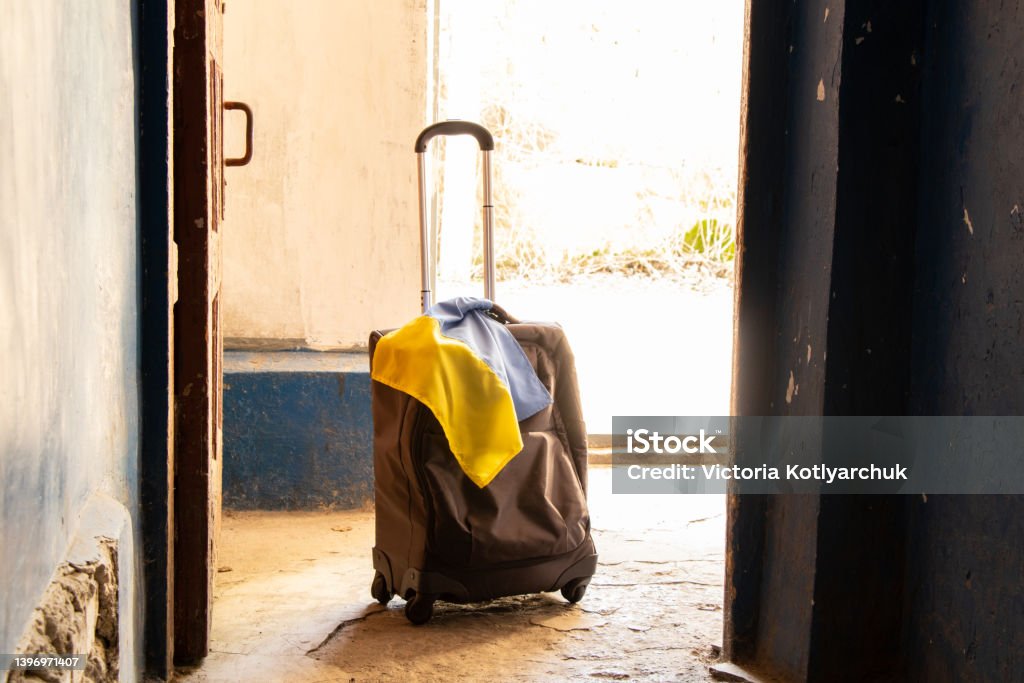 A suitcase with the flag of Ukraine stands in the entrance of the house, people leave their homes because of the war, Ukrainian refugees, the war in Ukraine, a suitcase A suitcase with the flag of Ukraine stands in the entrance of the house, people leave their homes because of the war, Ukrainian refugees, the war in Ukraine, a suitcase and travel Refugee Stock Photo