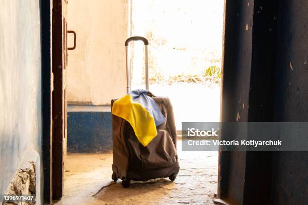 A Suitcase With The Flag Of Ukraine Stands In The Entrance Of The House People Leave Their Homes Because Of The War Ukrainian Refugees The War In Ukraine A Suitcase Stock Photo - Download Image Now