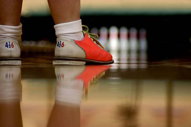 New Fangled Bowling Shoes Modern bowling shoes have bright colors. A low angle shot right along the alley showing shoes and their reflection in the highly polished wood. Focus is on bowler's shoes but the pins are visible in the background bowling alley wood stock pictures, royalty-free photos & images