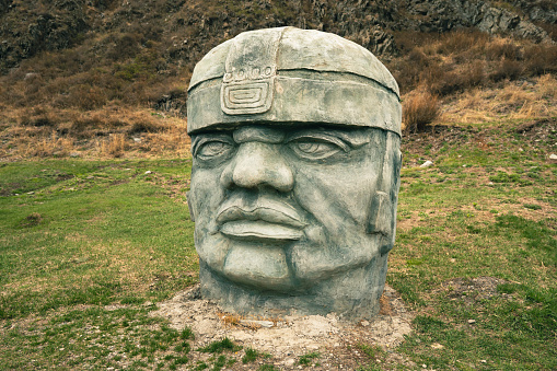 Olmec sculpture carved from stone. Mayan symbol - Big stone head statue in a nature