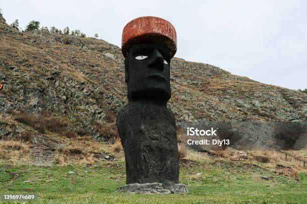 Stone Statue In A Red Hat Is Buried In The Ground Stock Photo - Download Image Now - Totem Pole, Landscape - Scenery, People