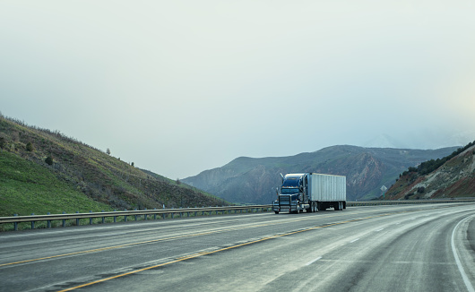 Blue and white semi-truck driving in Utah mountain range