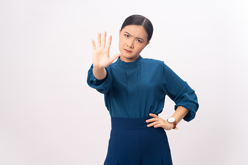 Asian woman showing hand making stop sign standing isolated on white background.